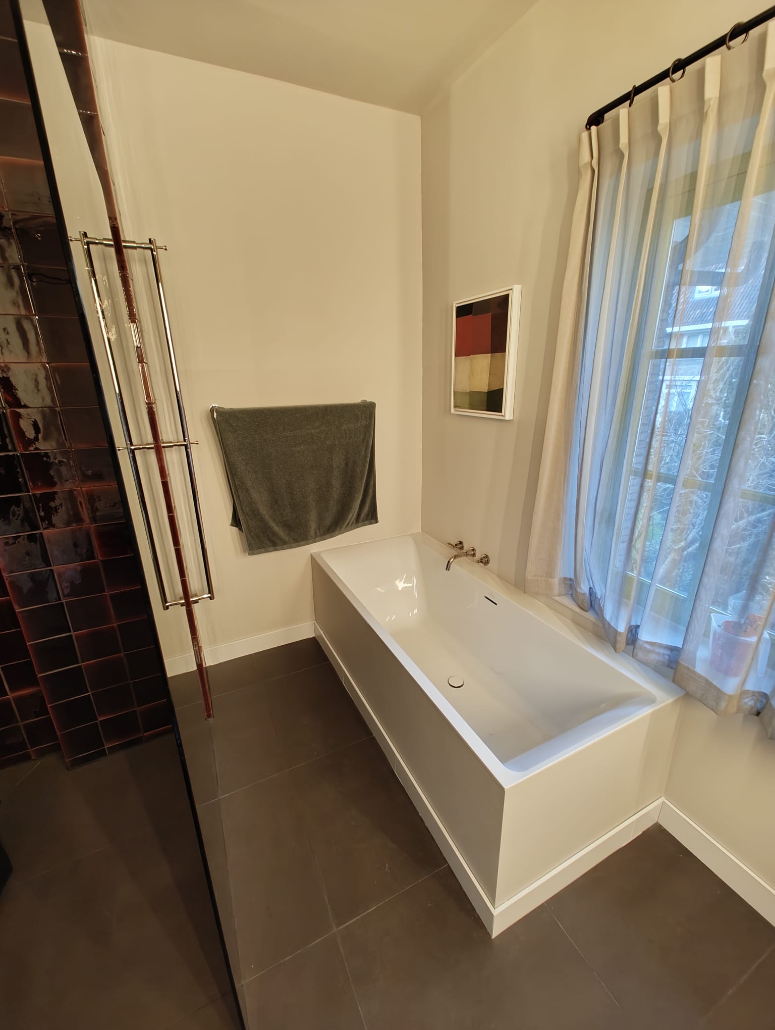 Freestanding bathtub with dark tile shower