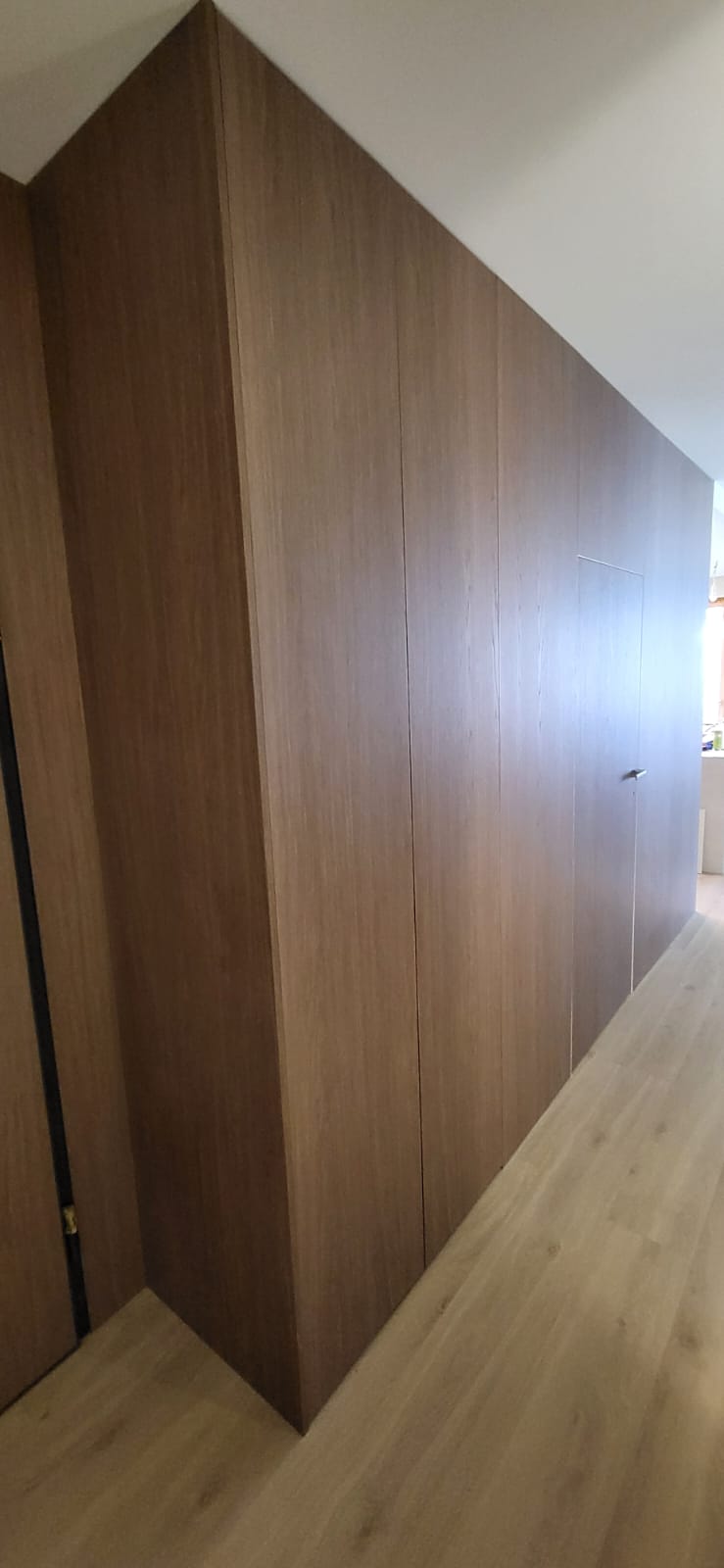 Full-height walnut wardrobe under sloped ceiling