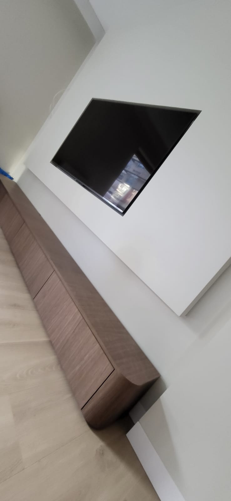 Floating walnut TV unit with recessed screen in plastered wall