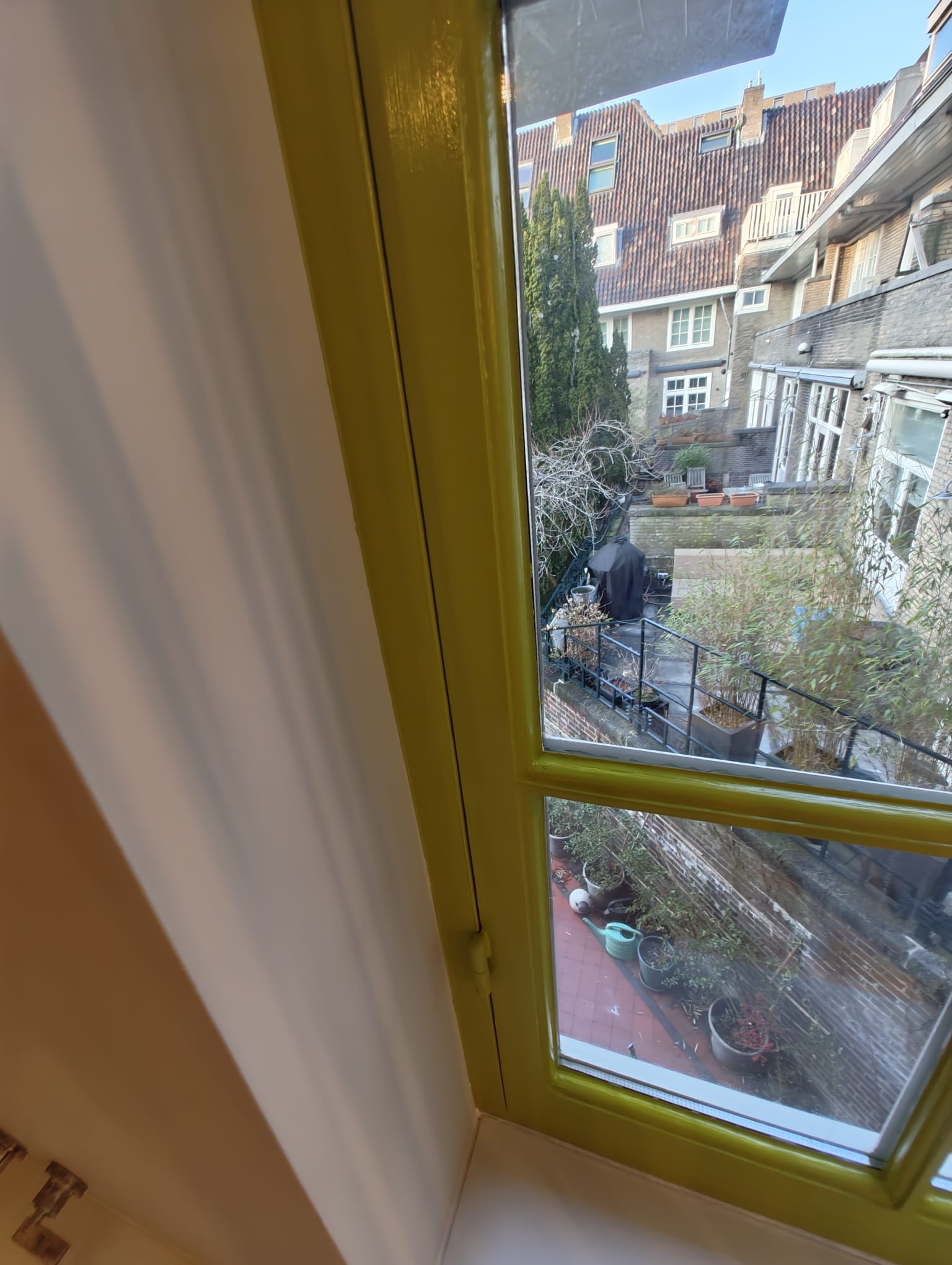 Restored Amsterdam canal house window with yellow painted frame