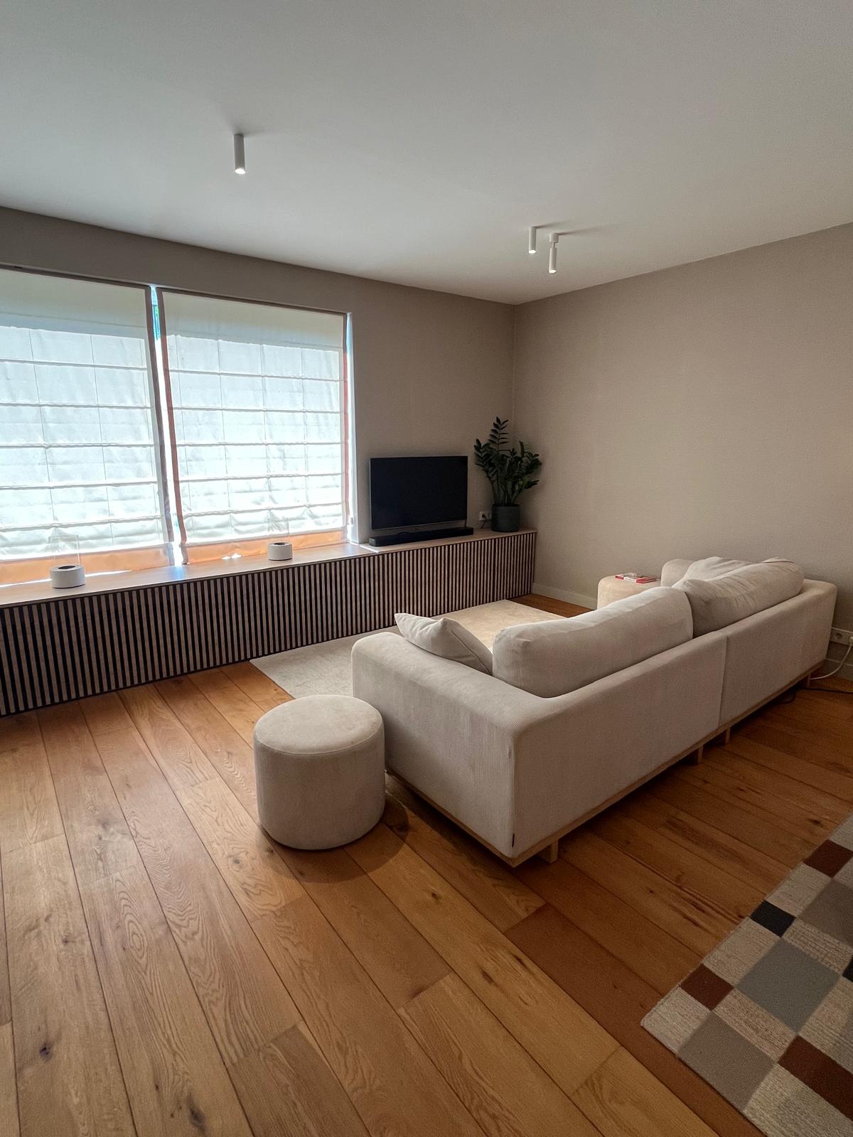 Living room with slatted oak media console beneath the windows