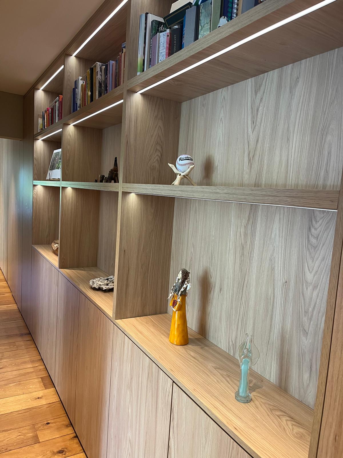 Floor-to-ceiling oak shelving with integrated LED strip lighting