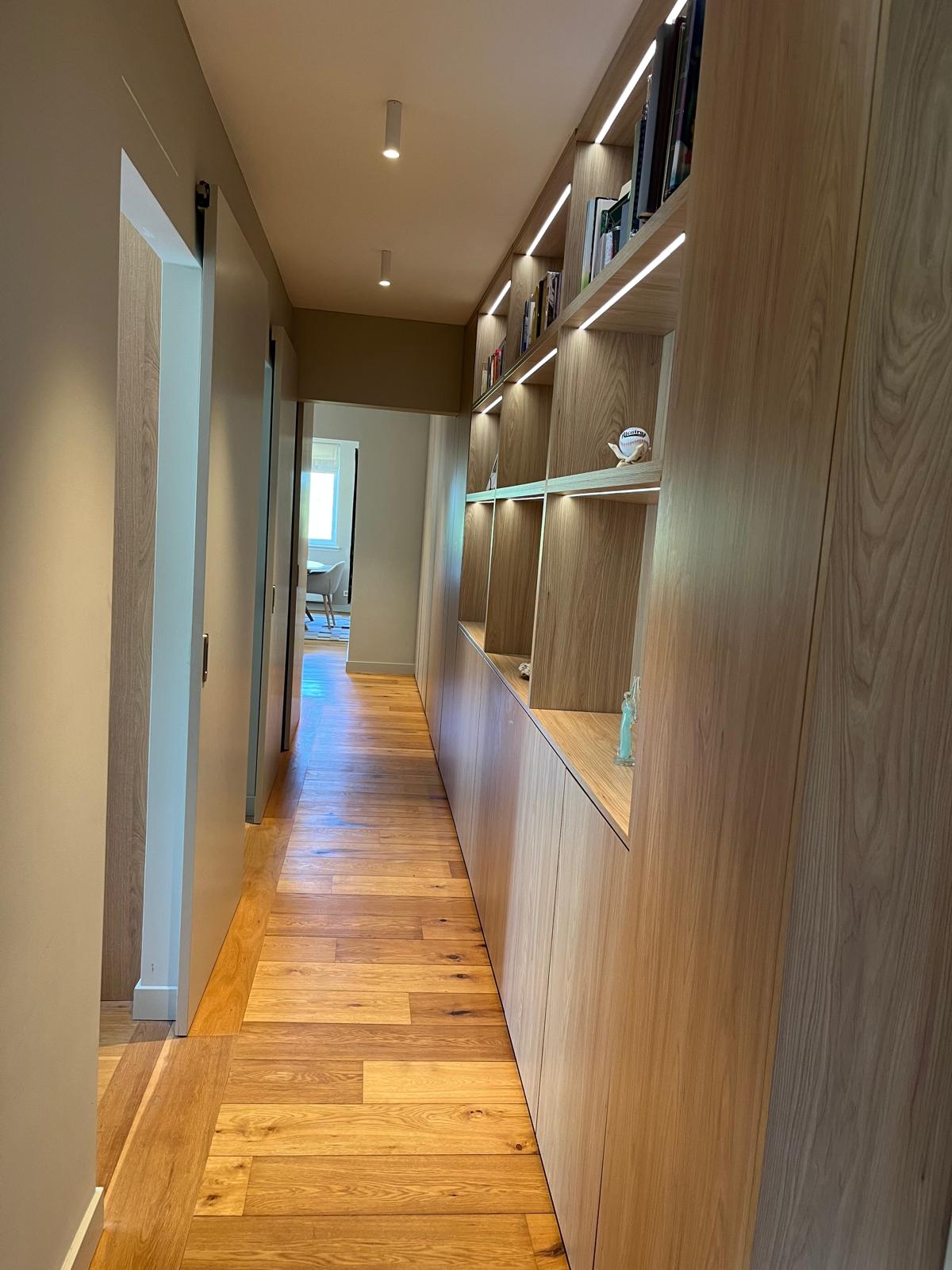 Hallway with lit open shelving and concealed wardrobe cabinets