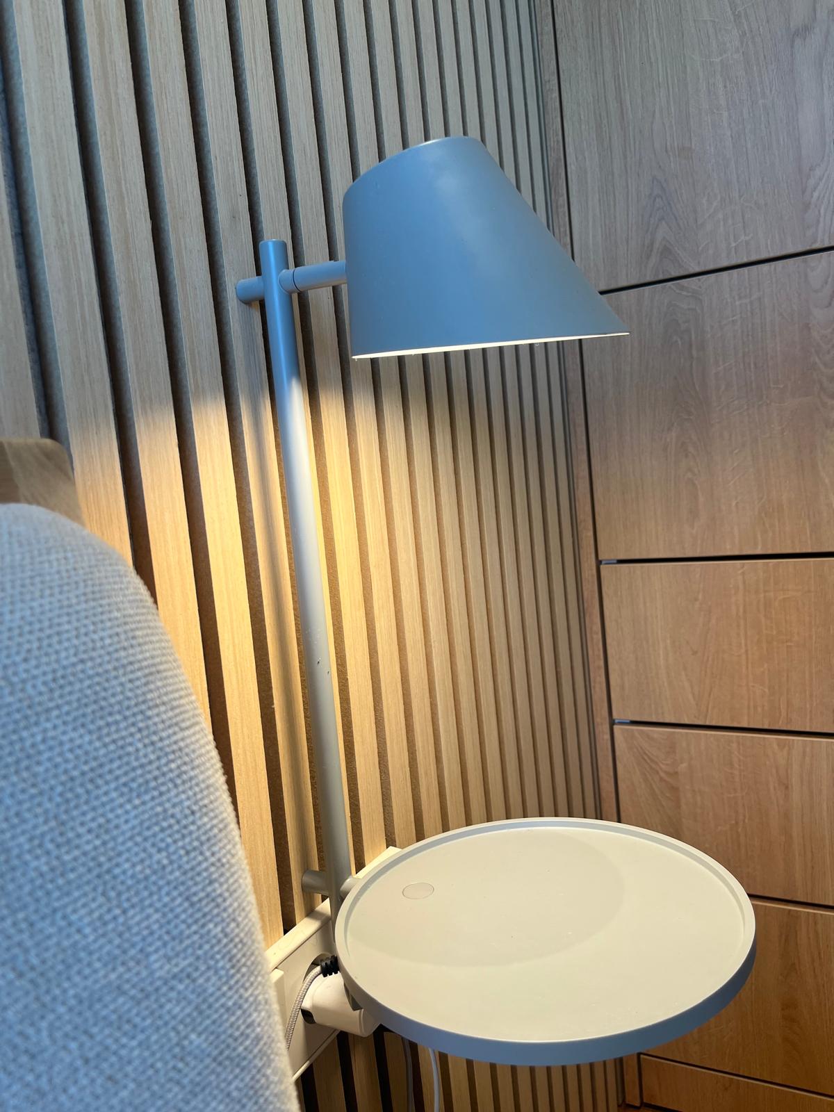 Wall-mounted bedside lamp and shelf against slatted oak headboard wall