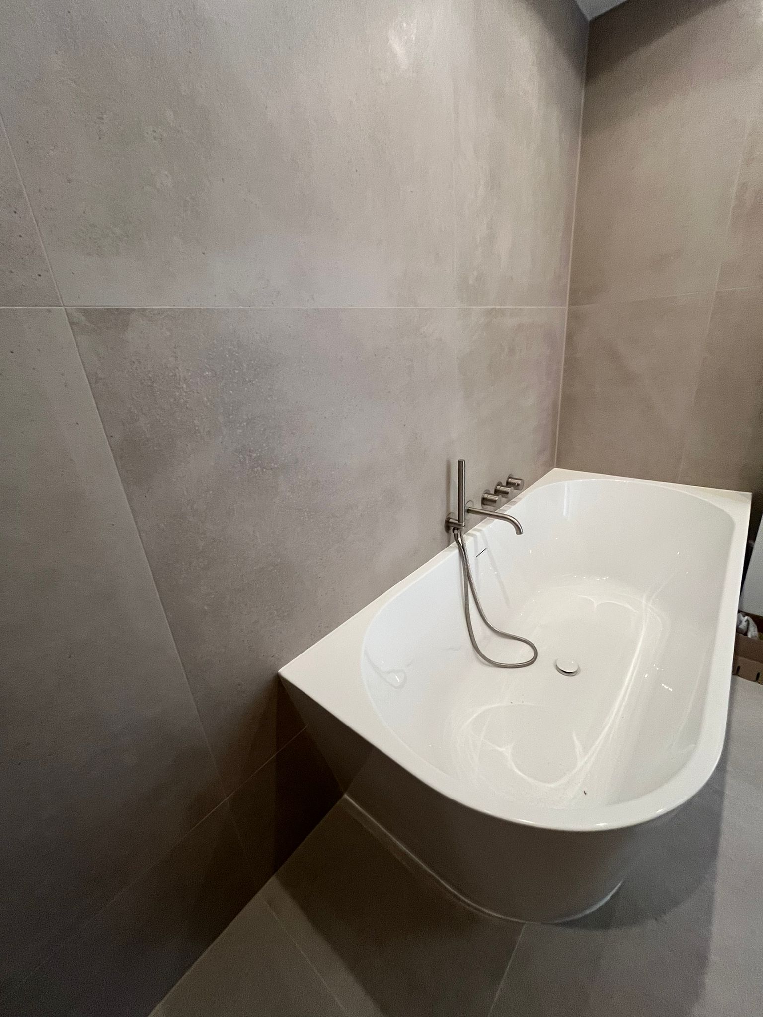 Freestanding oval bathtub with wall-mounted shower fittings