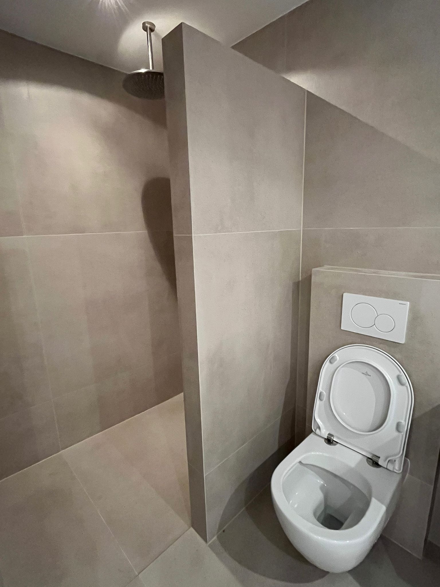 Tiled shower zone with rain shower and concealed cistern toilet